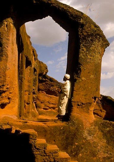 Priest praying by a rock church in Lalibela